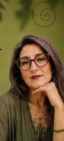 Mariangela con occhiali rossi, la mano appoggiata al mento, lo sguardo pensieroso